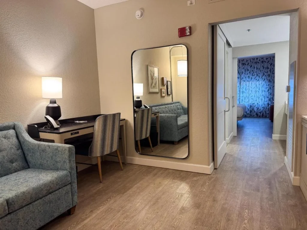 Suite living room with sofa, desk and sliding bedroom door at Caribe Royale Orlando