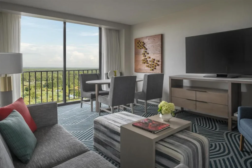 Sala de estar con sofá, mesa de comedor y ventanas de balcón de piso a techo en Hyatt Regency Grand Cypress
