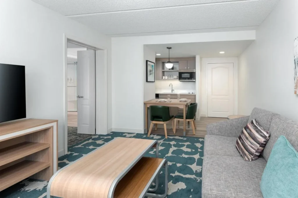 Suite salón con sofá, mesa de comedor y cocina en Homewood Suites Universal