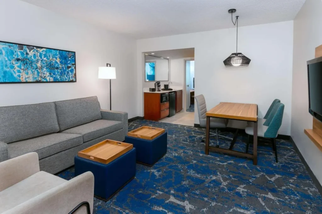 Suite sala de estar con sofá, mesa de comedor y bar en el Embassy Suites Tampa USF