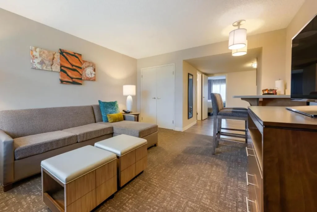 Suite living room with sofa, ottomans and a breakfast bar at Staybridge Suites Orlando Royale Parc