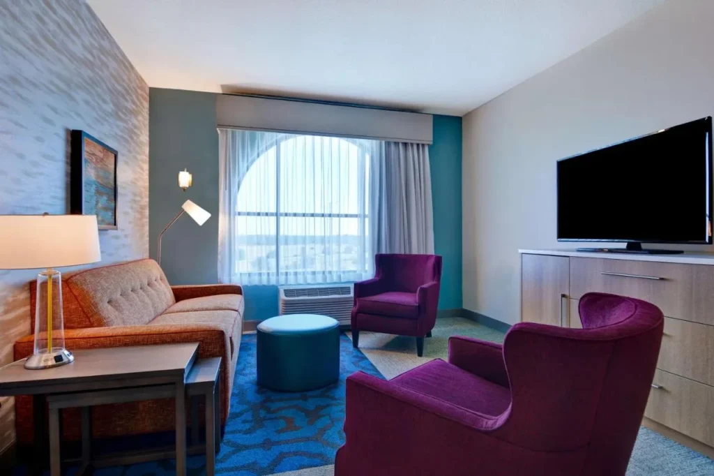 Sala de estar con sofá, sillones morados y TV grande en Home2 Suites Flamingo Crossings