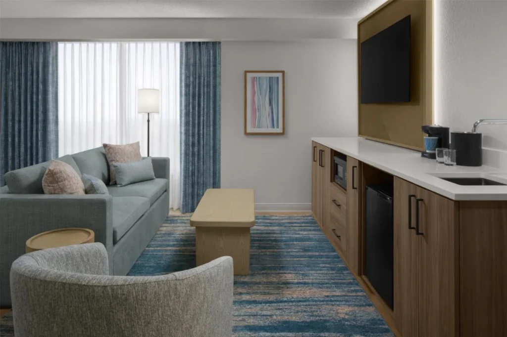 Sala de estar de la suite con sofá, bar y mini nevera en Embassy Suites ICON Park
