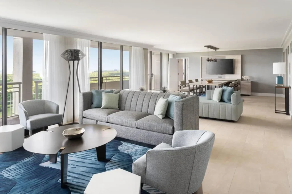 Sala de estar con sof&aacute;s, mesa de comedor y ventanas de piso a techo en el Orlando World Center Marriott