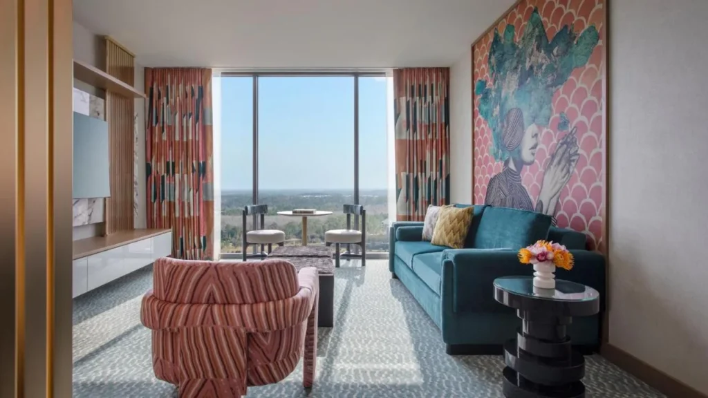 Sala de estar de la suite con sof&aacute; de color verde azulado, sill&oacute;n a rayas y mural grande en Lake Nona Wave Hotel