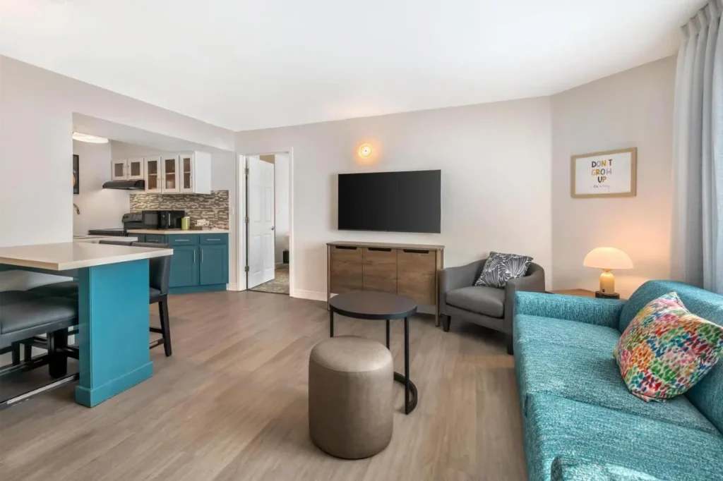 Sala de estar de la suite con sof&aacute; de color verde azulado, TV y barra de cocina, Sonesta ES Suites Lake Buena Vista