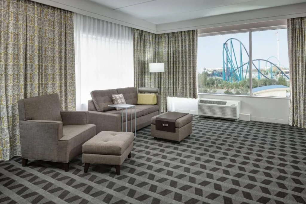 Suite con sofá y ventana frente a una montaña rusa SeaWorld, TownePlace Suites Orlando at SeaWorld