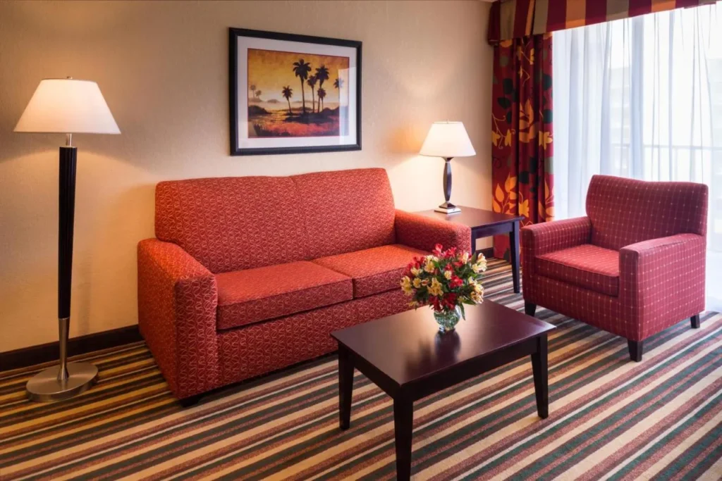 Suite con sof&aacute; rojo y sill&oacute;n en Holiday Inn & Suites Orlando SW