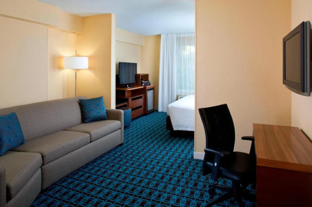 Suite with a sofa, desk and bed alcove at Fairfield Inn & Suites Marriott Village