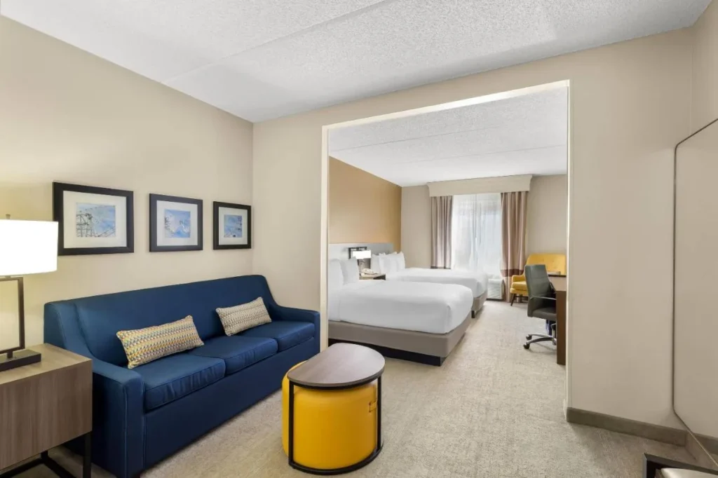Suite with blue sofa in front and two beds behind at Comfort Suites Near Universal