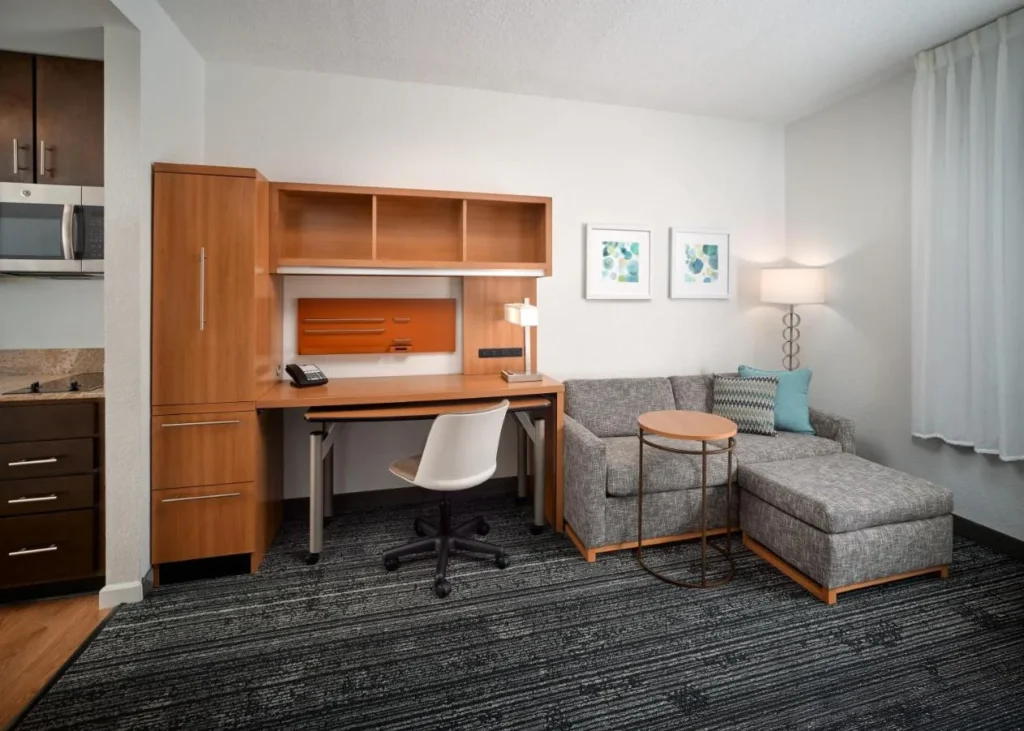 Suite with kitchen cabinets and microwave, built-in desk and sofa at TownePlace Suites Flamingo Crossings