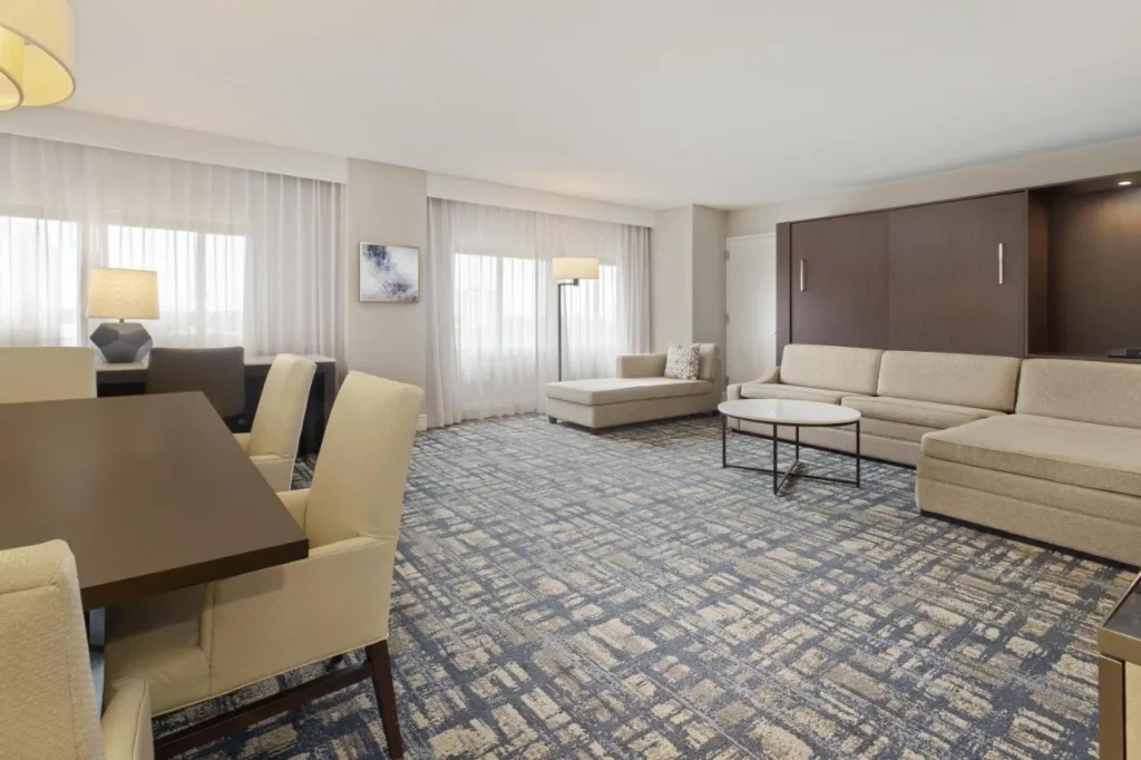 Suite con sof&aacute; seccional, mesa de comedor y cama de pared cerrada en Hilton Orlando Lake Buena Vista