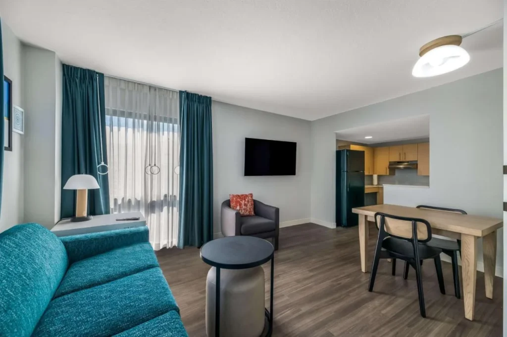 Suite con sof&aacute; de color verde azulado, mesa de comedor y cocina en Sonesta ES Suites Orlando - International Drive