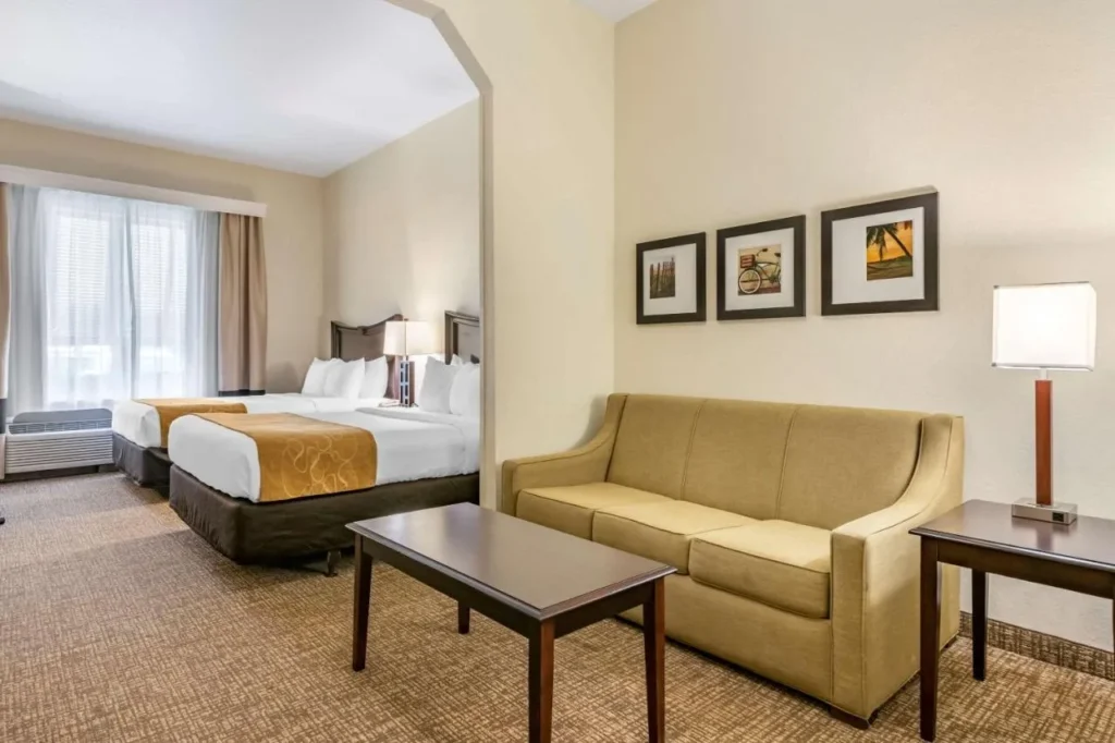 Suite con dos camas, un sofá y una mesa de centro en Comfort Suites Maingate East