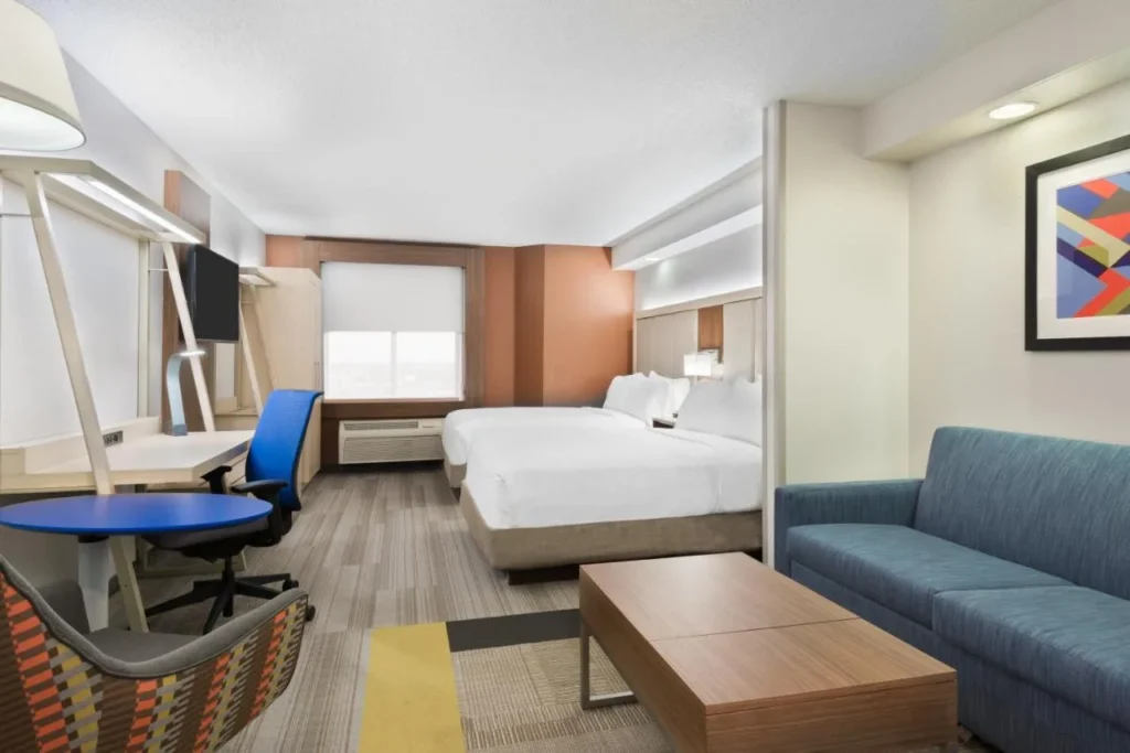 Suite with two beds, blue sofa, coffee table and desk at Holiday Inn Express Nearest Universal