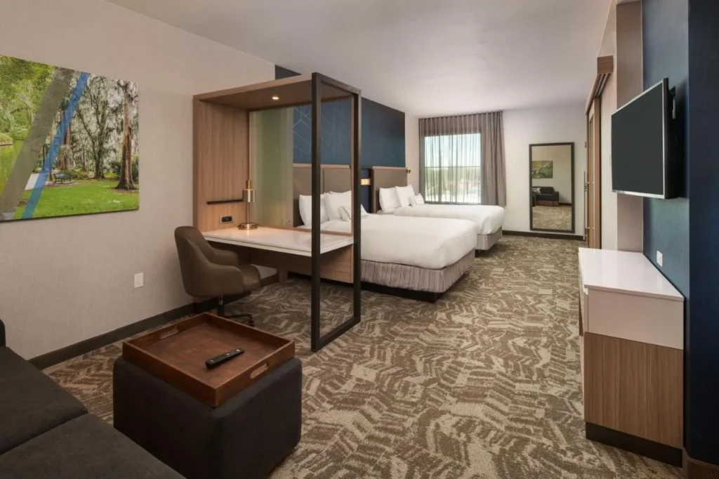 Suite con dos camas, escritorio y sofá en SpringHill Suites Winter Park