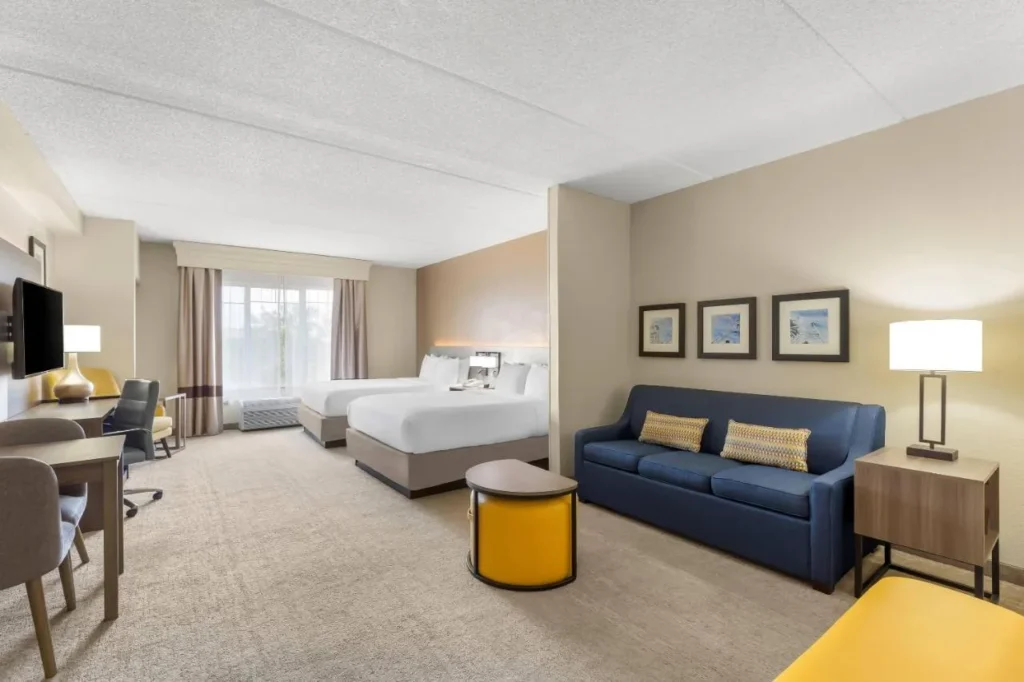 Suite with two queen beds, blue sofa and desk at Comfort Suites Near Universal Orlando Resort