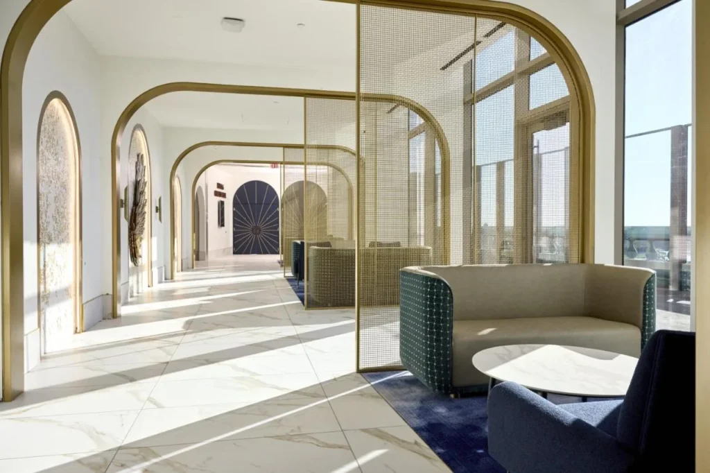 Sunlit lounge corridor with gold arches, sofas and marble floors at Universal Helios Grand Hotel