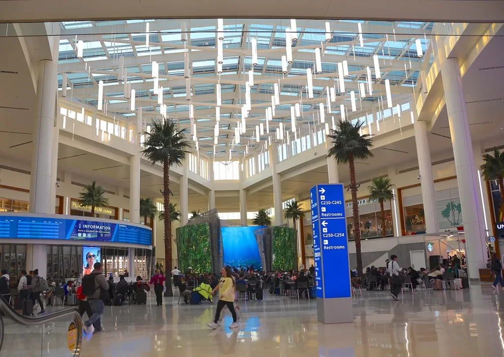 Sunlit Terminal C hall at Orlando International Airport with palm trees, gate signs and travelers