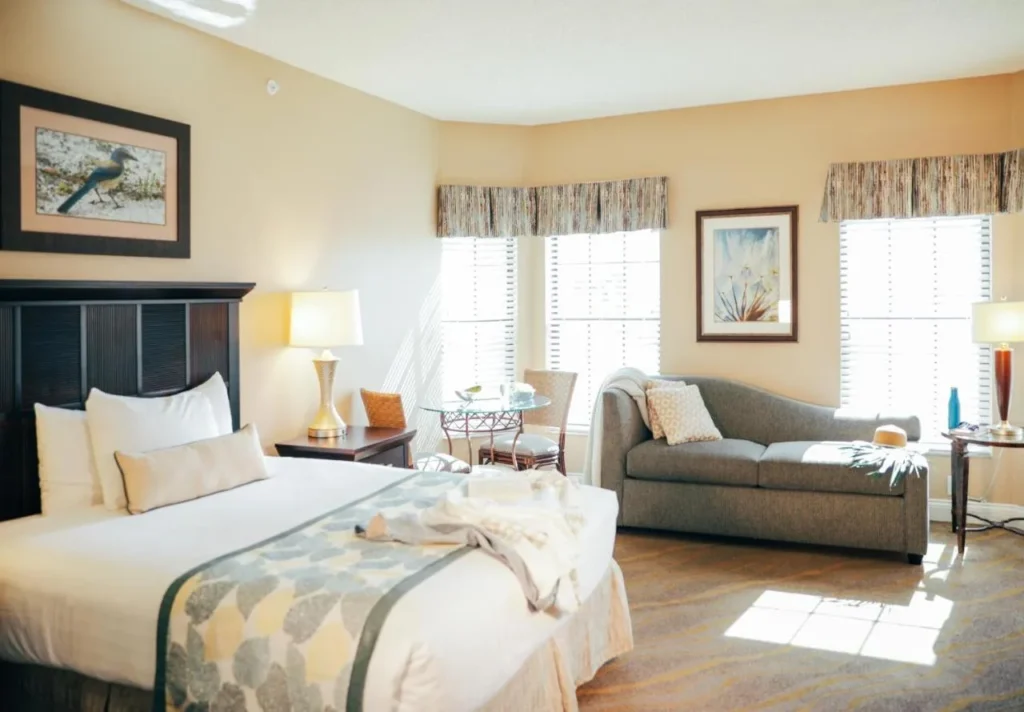 Sunny bedroom with a large bed, sofa and bistro table at Orange Lake Resort