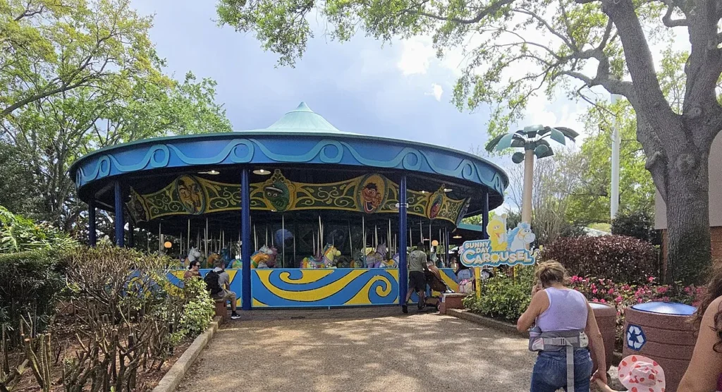 Sunny Day Carousel with Sesame Street characters under shade trees in Sesame Street Land, SeaWorld Orlando
