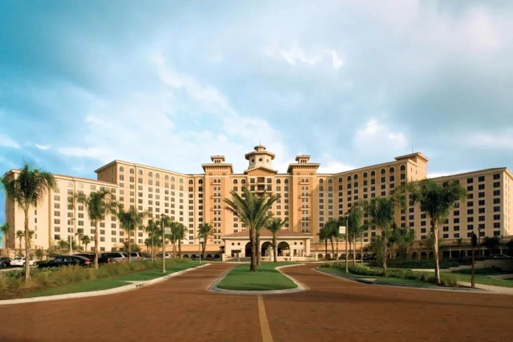 Edificio alto de estilo mediterráneo y entrada bordeada de palmeras en Rosen Shingle Creek