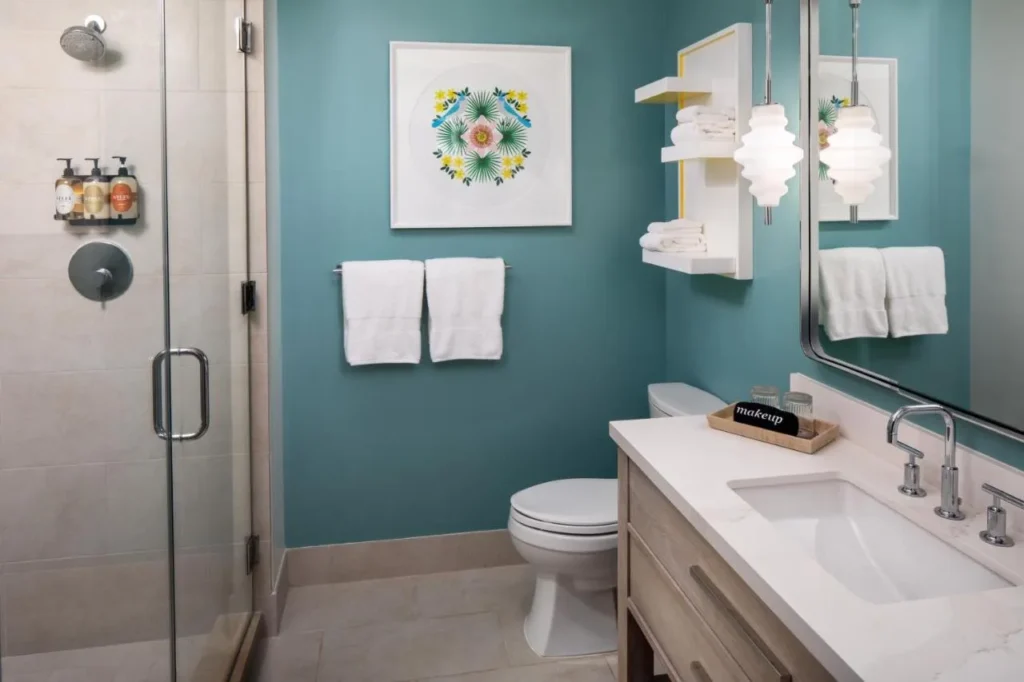Teal guest bathroom with glass walk-in shower and vanity at The Alfond Inn