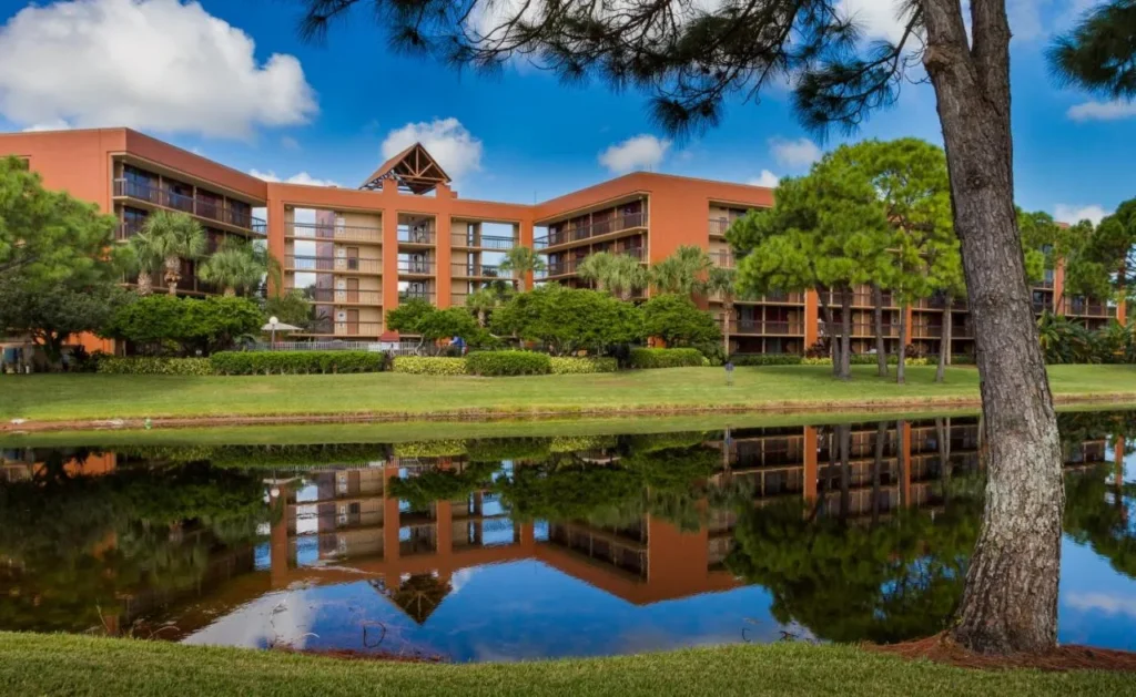 Terracotta guest buildings reflected in a pond at Rosen Inn Lake Buena Vista