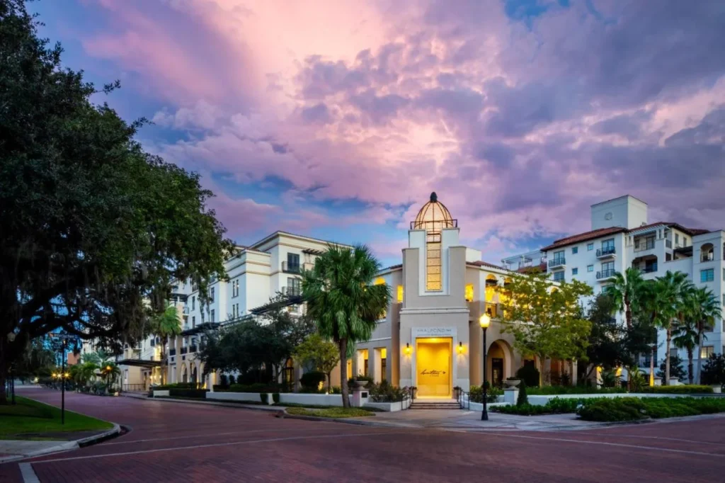 El Alfond Inn al atardecer, con su torre abovedada iluminada y palmeras en Winter Park