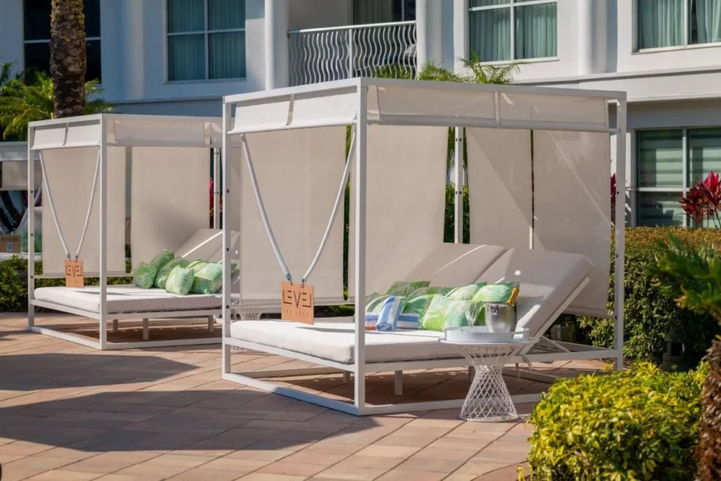 Camas de día The Level junto a la piscina con toldos blancos y cojines verdes en Meliá Orlando Celebration