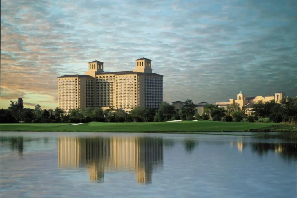 Las torres Ritz-Carlton Orlando, Grande Lakes se reflejan en un lago bajo un cielo pastel