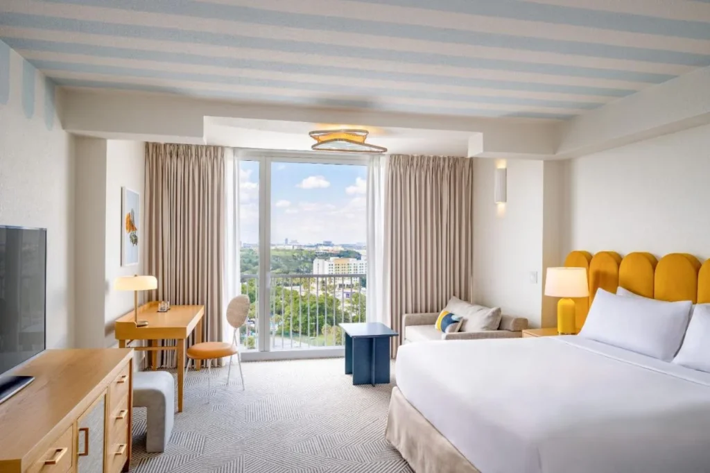 Habitación Tower king con cabecera amarilla, sofá, escritorio y ventana con vista a la ciudad en Renaissance Orlando Resort