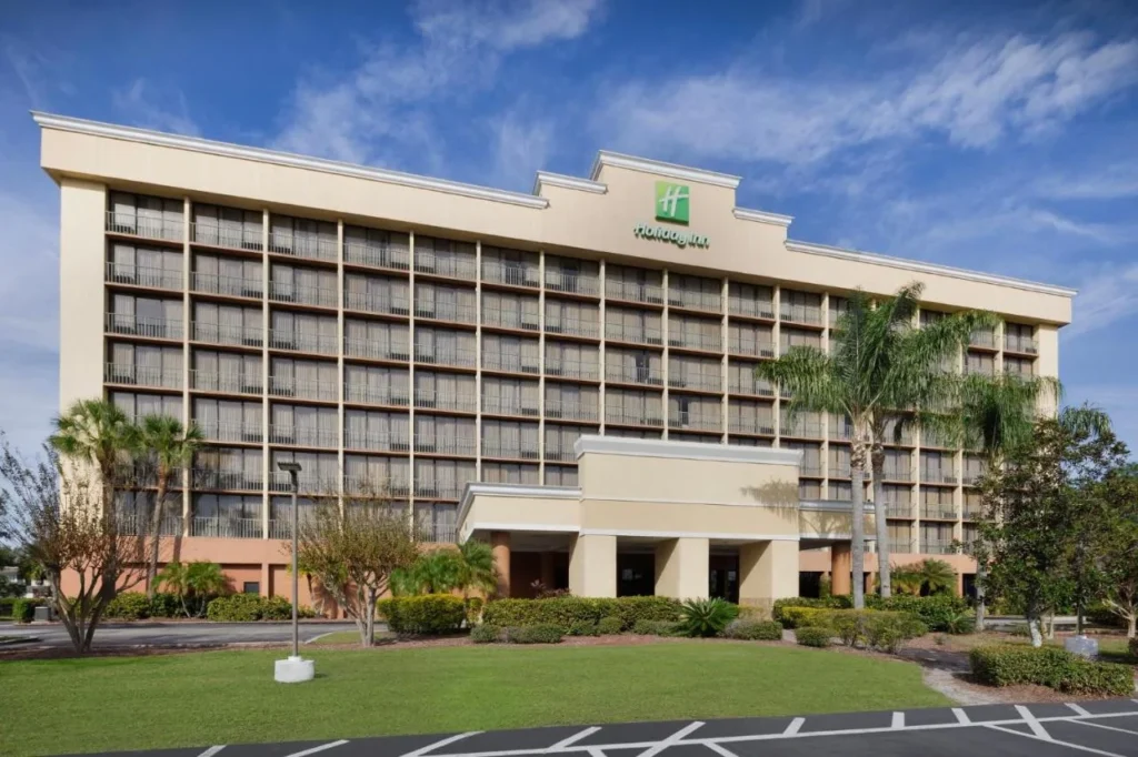 Tower with balconies, palm trees and a covered entrance at Holiday Inn & Suites Orlando SW