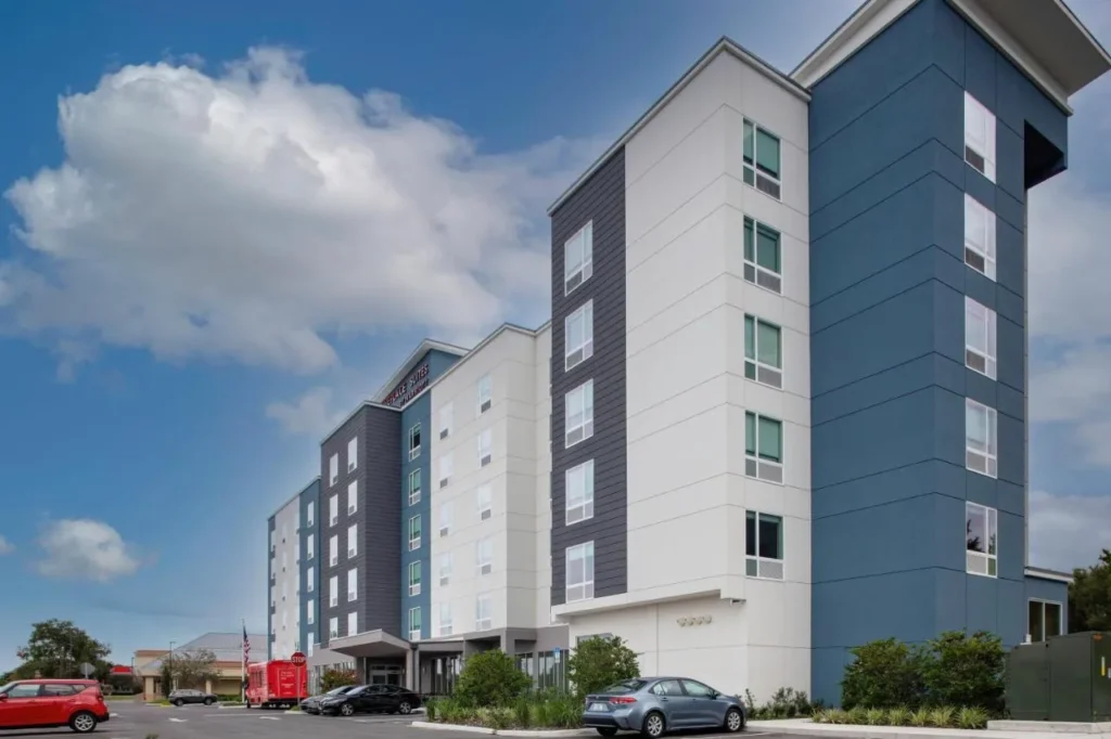 TownePlace Suites Orlando Airport tower above its parking lot under a blue sky
