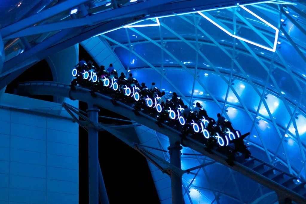 TRON Lightcycle / Run train with glowing lightcycles under its illuminated canopy at night, Magic Kingdom