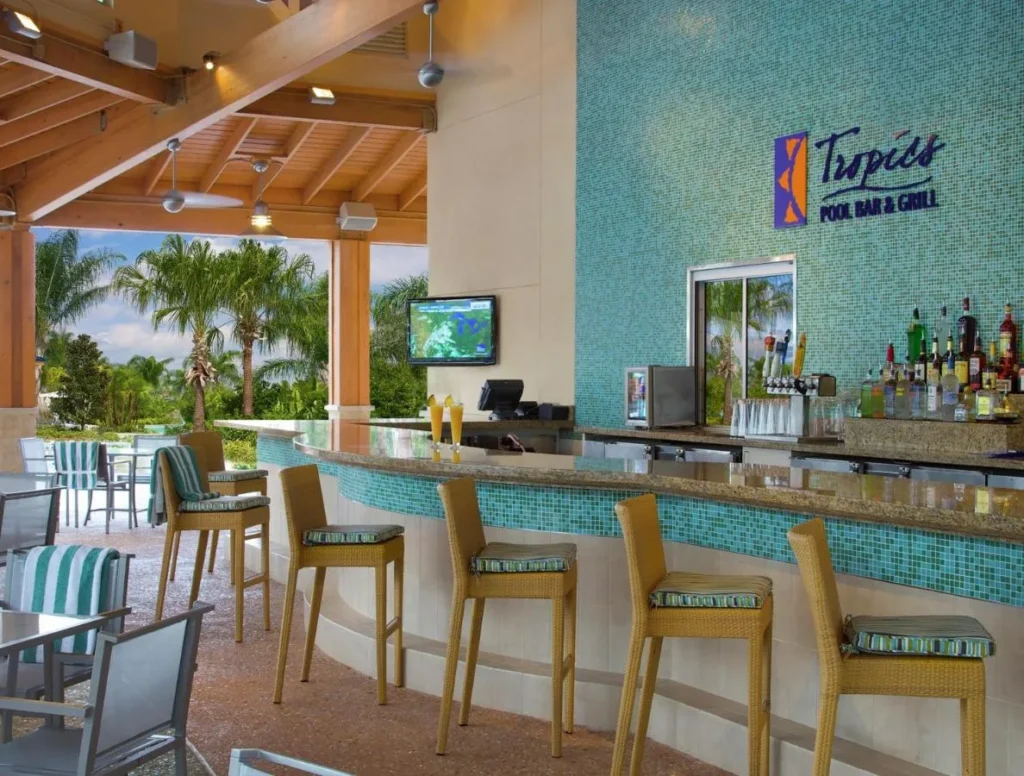 Tropics Pool Bar and Grill counter with wicker stools and palm views at Hilton Orlando