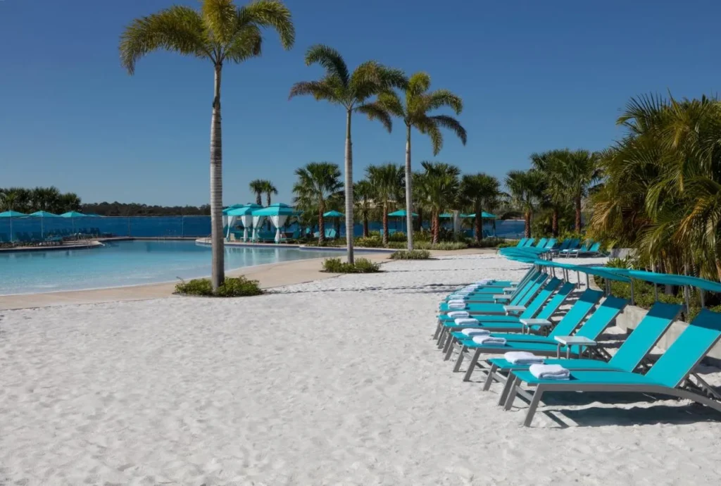 Tumbonas turquesas en la playa de arena junto a la piscina de la laguna en Margaritaville Resort Orlando