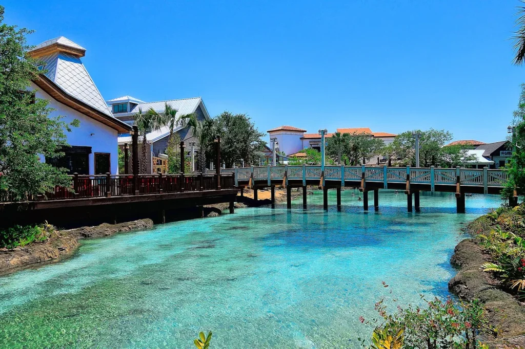 Turquoise waterway, wooden footbridge and waterfront restaurant buildings at Disney Springs on a sunny day