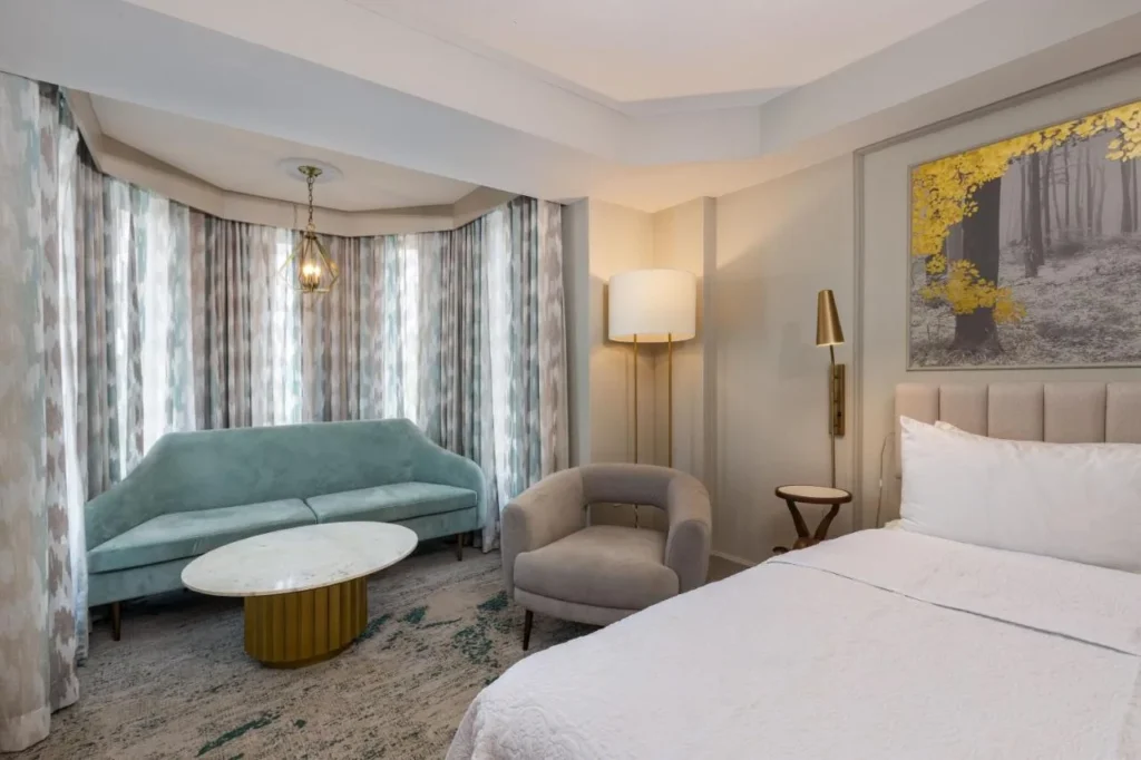 Turret seating nook with a teal sofa and armchair in a Castle Hotel Orlando tower room