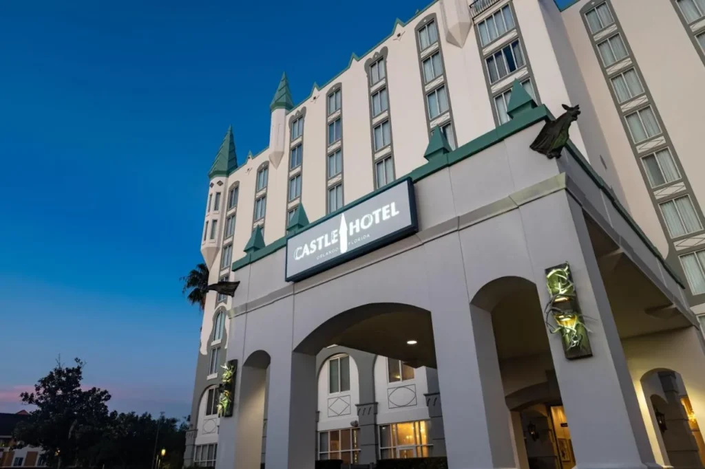 Turreted white facade and lit entrance canopy with the hotel sign at Castle Hotel, Autograph Collection