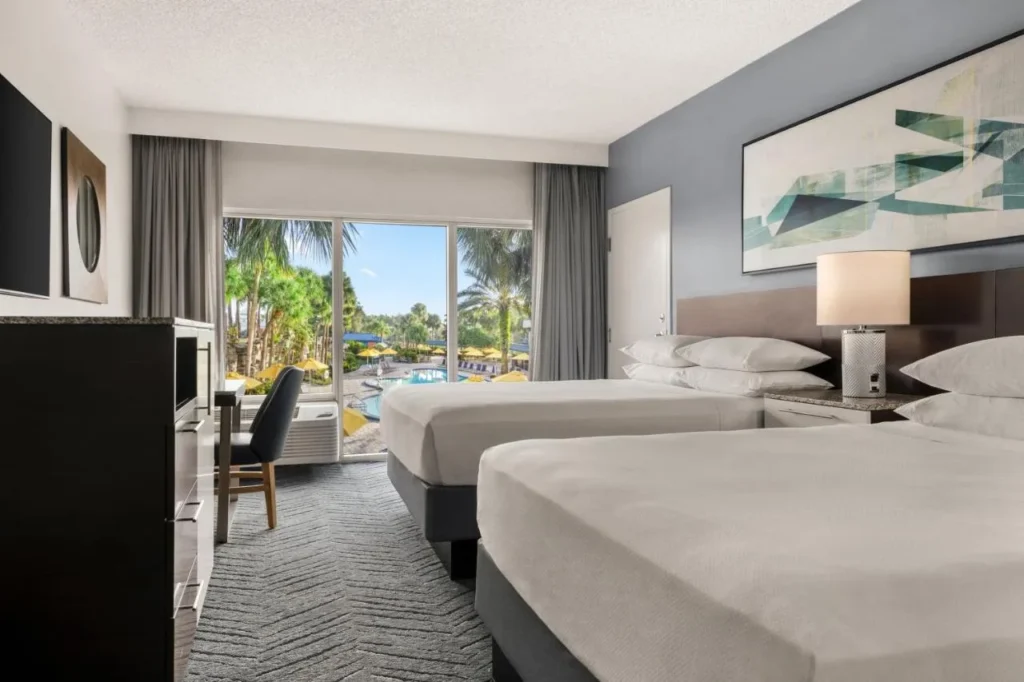 Habitación de dos camas con vista a la piscina a través de la ventana en Delta Hotels Orlando Celebration