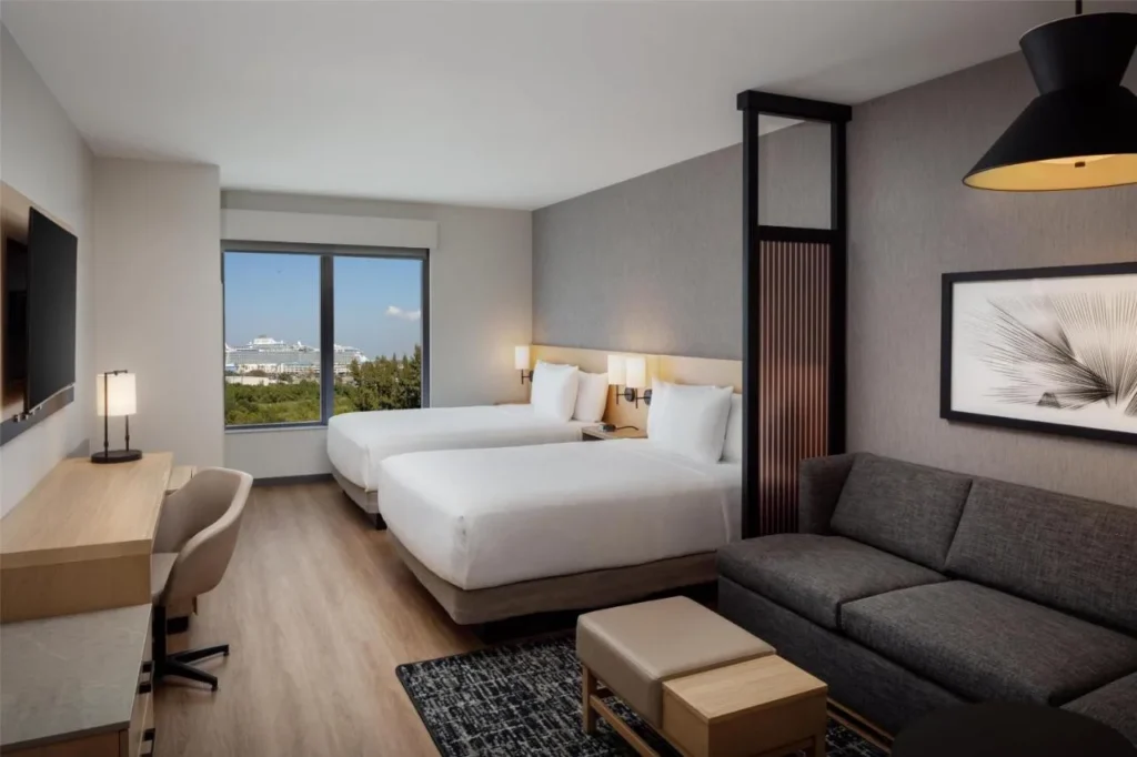 Two-bed guest room with sofa and a cruise ship visible through the window, Hyatt Place Cape Canaveral