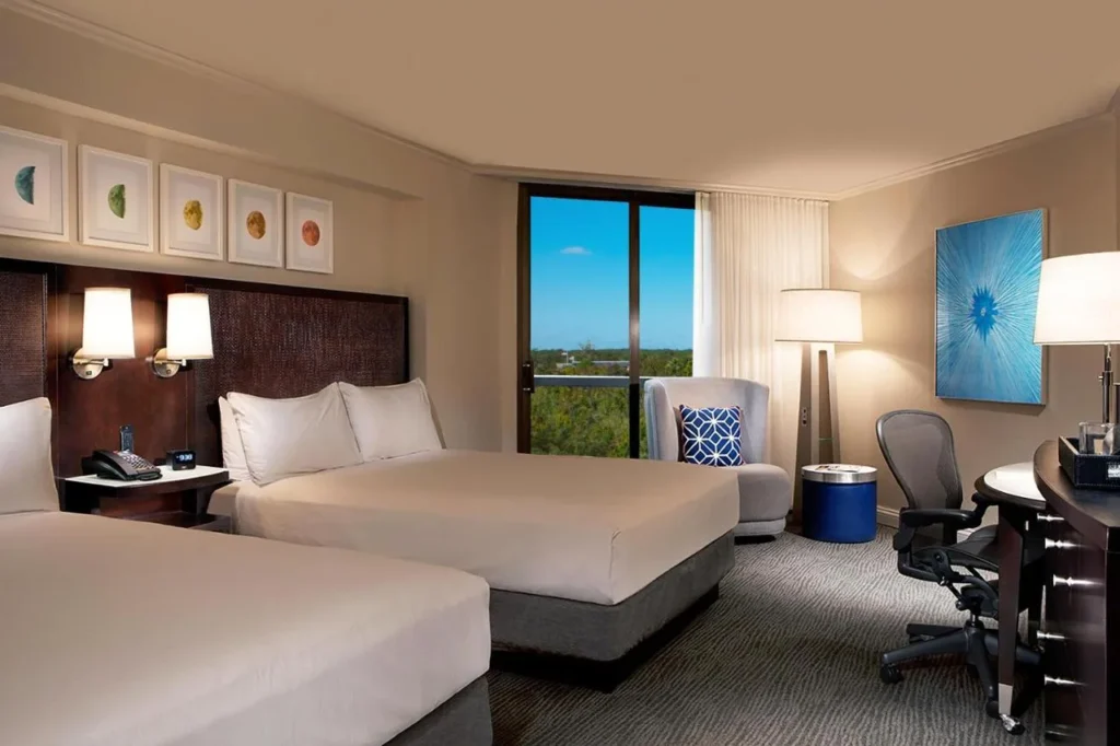 Two-bed room with a tall window and armchair at Hilton Orlando Buena Vista Palace