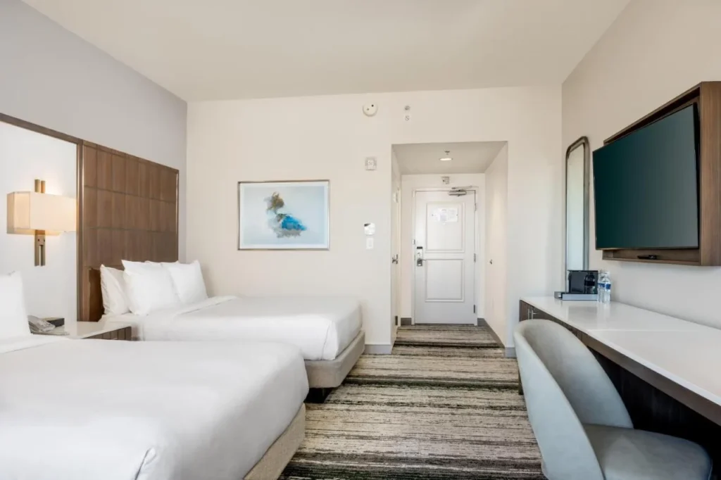 Habitaci&oacute;n de dos camas con TV de pared y escritorio en Signia by Hilton Orlando Bonnet Creek