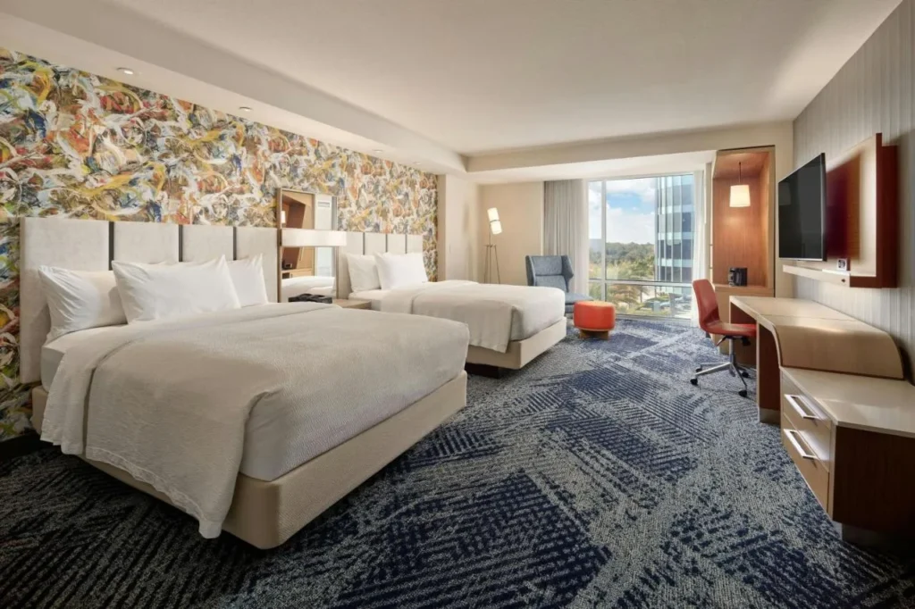 Habitaci&oacute;n de dos camas con cabecera floral y ventana alta en el Courtyard Orlando Lake Nona