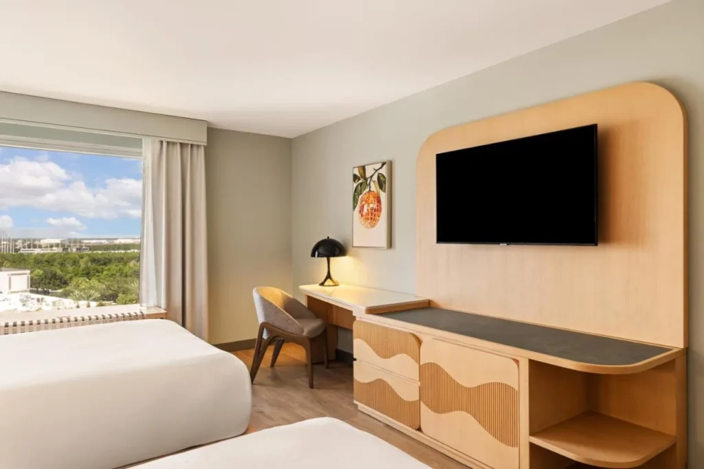 Two-bed room with wall TV, desk and a high-floor window view at Rosen Plaza Hotel