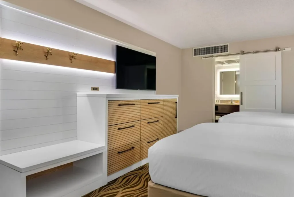 Two-bed room with wood dresser, TV and sliding bathroom door at Wyndham Garden Lake Buena Vista