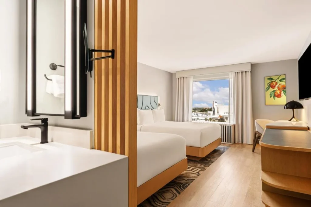Two-bed room with wood-look floors, a vanity sink and a city view at Rosen Plaza Hotel