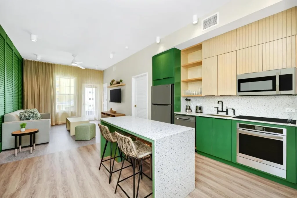 Two-bedroom suite kitchen with green cabinets and island at Embassy Suites Orlando Sunset Walk