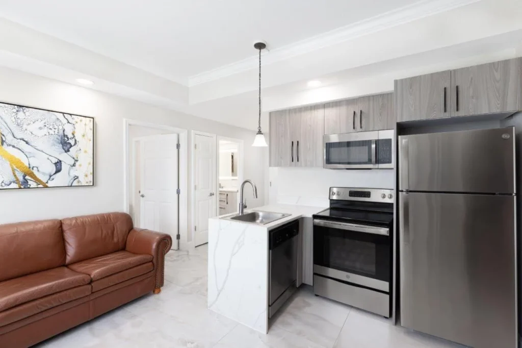 Two-bedroom suite kitchen with stove, dishwasher and refrigerator beside a leather sofa at Westgate Palace